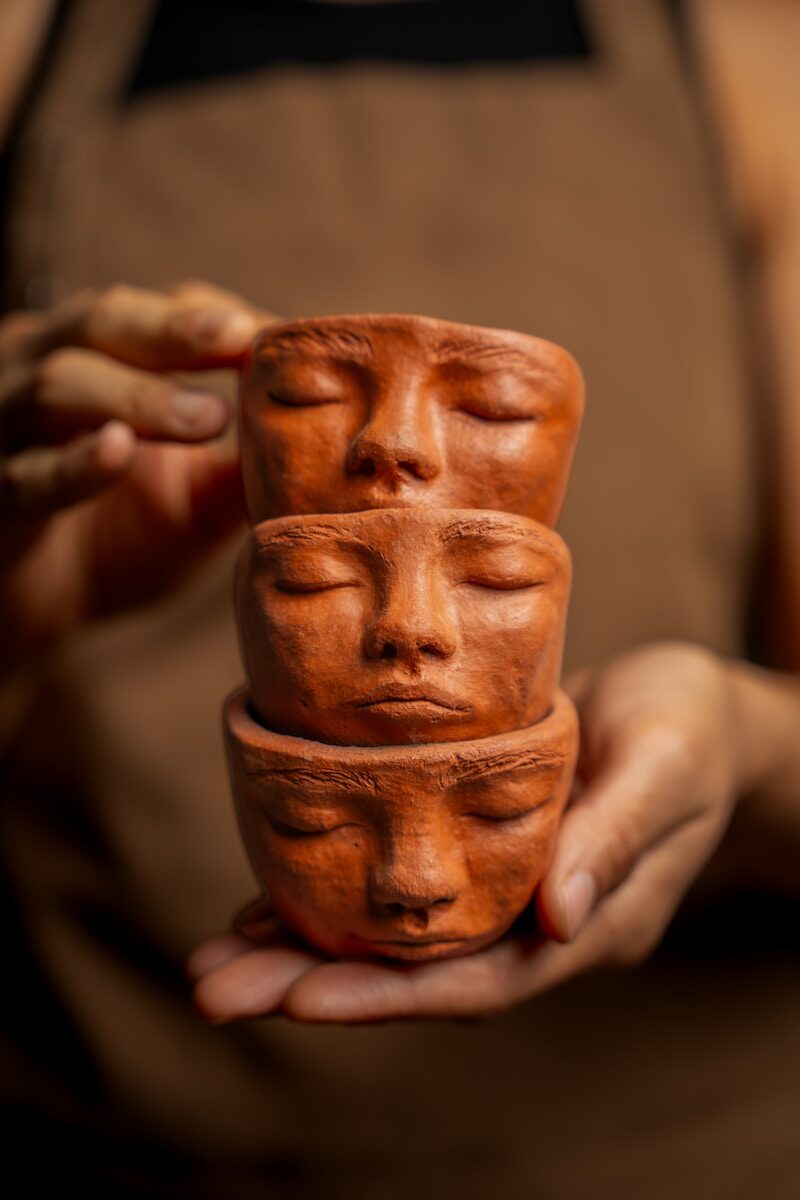 Three stacked terracotta pots shaped like faces.
